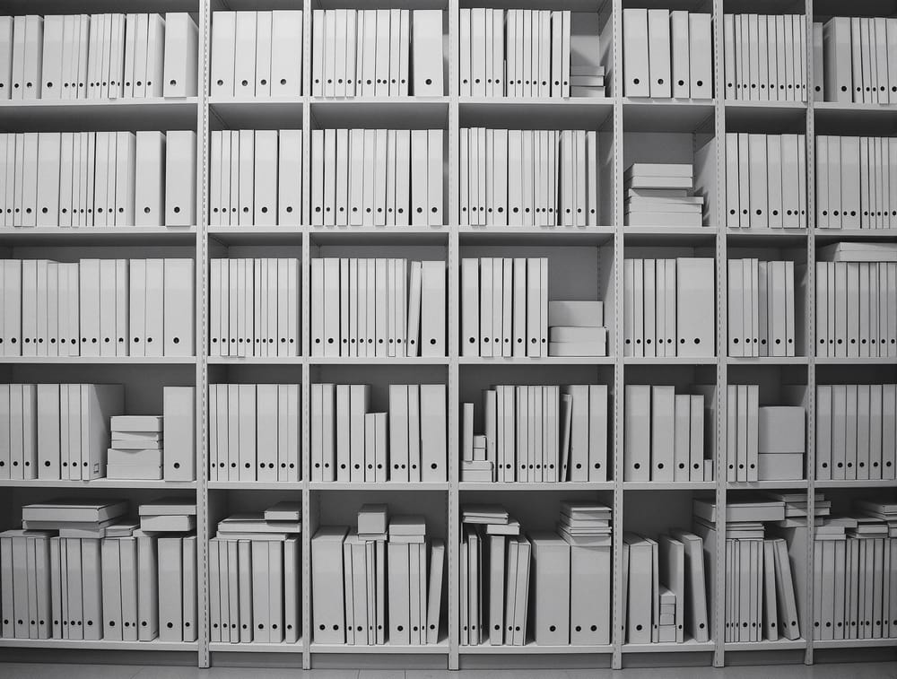 Orderly open shelving of plain uniform boxes and folders, photographed wide, with no legible labels.
